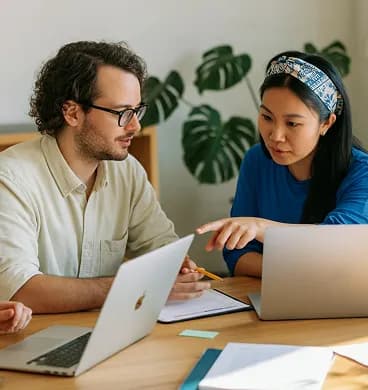 Colleagues discussing work at laptops